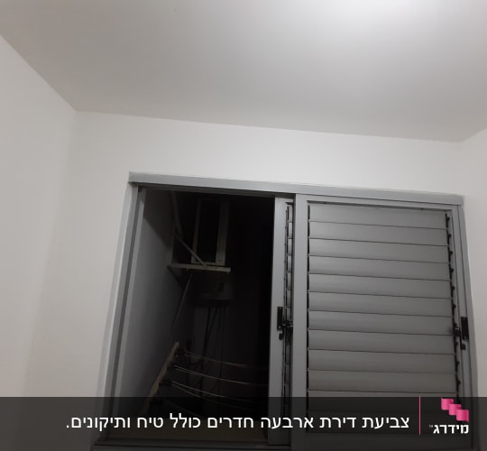 חלון עם תריסים אפורים על קיר לבן
